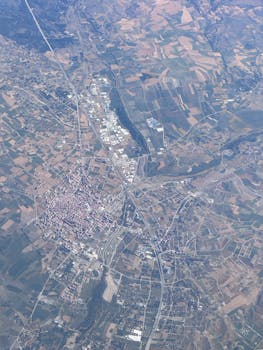 High-angle aerial shot capturing vast fields and towns, showcasing rural landscape patterns.