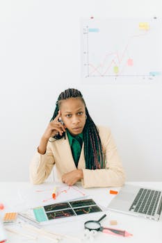 Professional woman analyzing financial graphs and data at an office desk, showcasing business expertise.