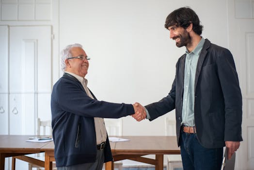 Two business professionals shaking hands in a bright office, symbolizing successful collaboration.